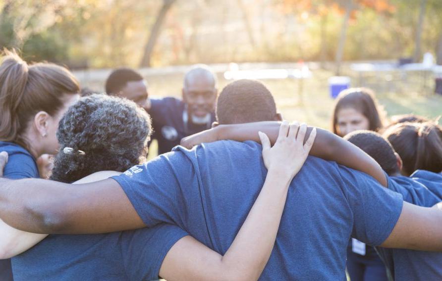 Group of diverse employees in a huddle with arms around each other